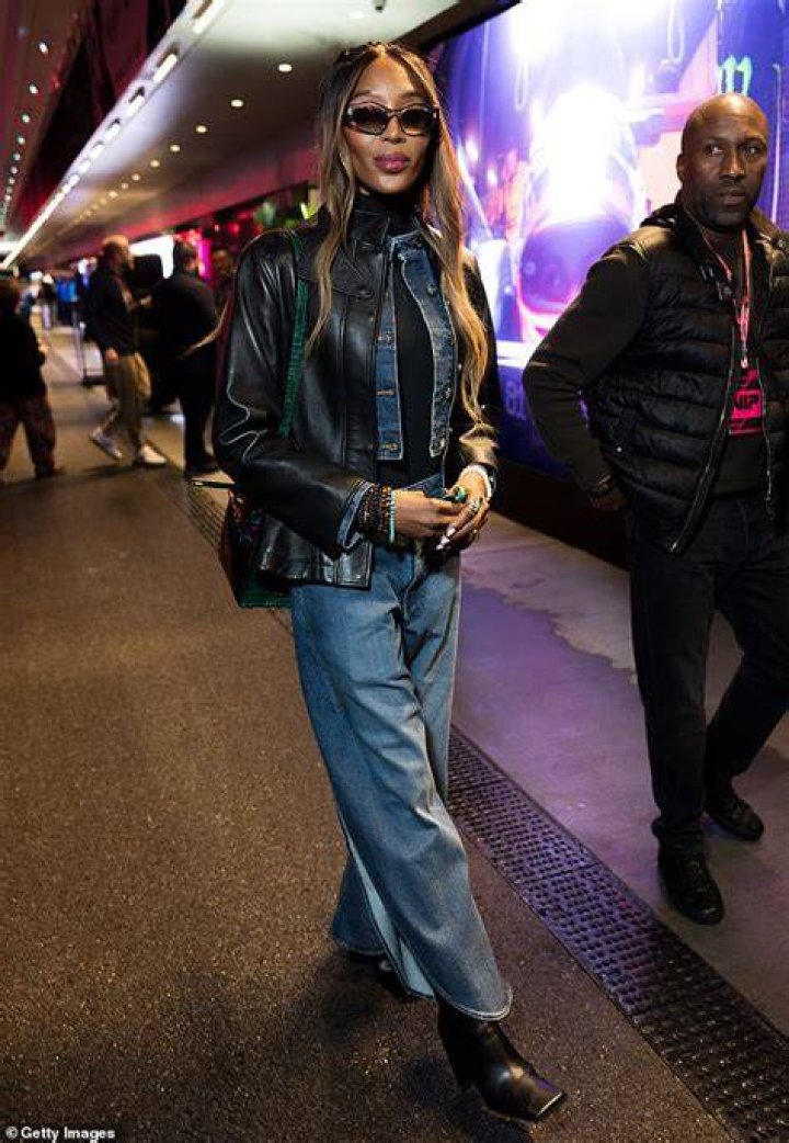 Layering up: The supermodel was spotted wearing a large black overcoat on top of a pair of multicolored track pants during her trip